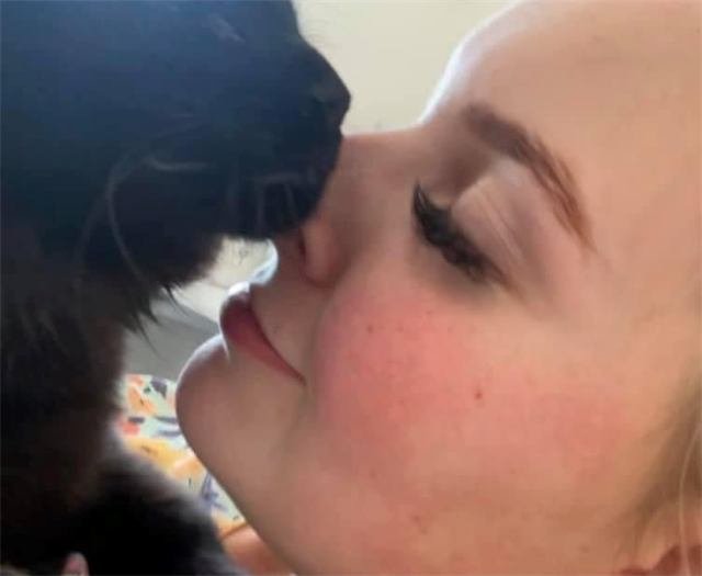 A black cat nuzzling a woman's nose