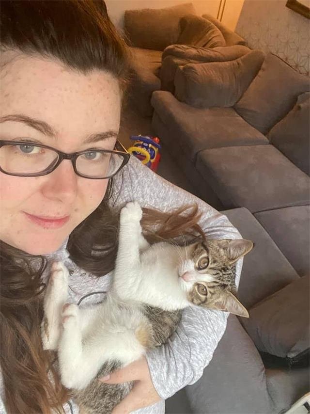 A woman holding a tabby and white kitten in her arms